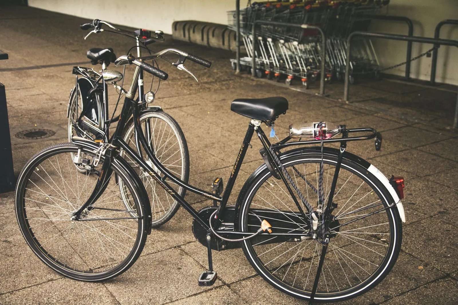 Two classic bicycles parked on a city street, offering a vintage transportation vibe.